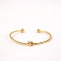 Gouden open armband detailweergave, minimalistisch metalen knoop ontwerp glanzende finish. - Stijl 1 / Goud