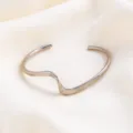 Close-up detail van minimalistische gegolfde metalen open armband met geometrisch design. - Stijl 2 / Zilver