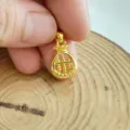 Close-up detail van een gouden geldzak abacus hanger met fijne afwerking en textuur. - Geldzak en Abacus Hanger Zonder Ketting