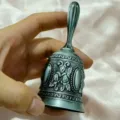 Close-up van vintage in reliëf gemaakte metalen handbel met bloemmotief en handvat. - Gesneden / 11x5cm / Antiek Zilver