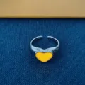 Zilverkleurige open ring met een heldergeel hartmotief in een modieuze minimalistische stijl. - Lichtgevend Geel