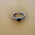 Close-up van retro open ring met zwarte cirkel en kettingband detail voor dagelijks gebruik. - Zwart