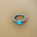 Detailopname van de retro verstelbare zilveren ring met stralende blauwe steen. - Lichtgevend Blauwgroen