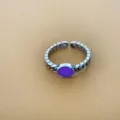 Gedetailleerd shot van retro zilveren open ring met paarse steen en uniek kettingontwerp. - Lichtgevend Paars