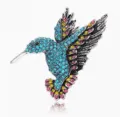 Detailopname van een prachtige kristallen kolibriebroche met schitterende blauwe en roze strass. - Oud Zilver Meerblauw