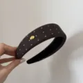 Primo piano di un cerchietto marrone a pois con un delicato dettaglio di logo in metallo. - Stile Etichetta Oro Spugna Pois Marrone / 4cm / Caffè