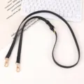 Detailed view of the black adjustable leather bag strap featuring gold-tone metal hardware. - Black