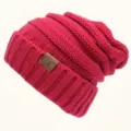 Detailed view of red knit slouchy beanie featuring thick ribbed brim and leather patch. - One Size / Rose Red
