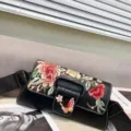 Détail de broderie du sac à bandoulière noir vintage avec motifs floraux et large sangle. - Noir