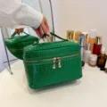 Grüne Kosmetiktasche mit Krokomuster, Griff und Doppelreißverschluss für Make-up. - Grün
