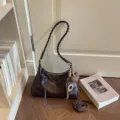 Sac bandoulière marron foncé en cuir avec bandoulière tressée élégante et accessoire pendentif. - Avec Pendentif / Café