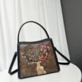 Detail shot of brown faux leather crossbody bag featuring exquisite floral deer embroidery design. - Coffee