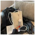 Witte mini crossbody tas voor dames van zacht leer met elegant knoopdetail en riem. - Broken Wit