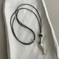 Detailed shot of the metal fish pendant and tiger eye stone bead on the necklace cord. - Style 2 (Fish Pendant)
