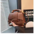 Brown textured leather mini handbag with top handle and curved flap for women stylish. - Brown
