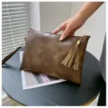 Gros plan détaillé du sac clutch en cuir marron rétro avec texture unique et pompon chic. - 28*18*1cm / Kaki