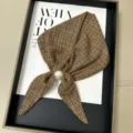 Vue détaillée d'un petit foulard en soie à carreaux marron avec boucle de perles. - Carreaux Marron