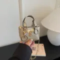 Mini metallic handbag charm with chain strap and padlock detail, closeup product detail view. - Gold
