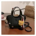 Detailed view of black leather tote bag with cute bear keychain and stylish ribbon decoration. - With Pendant / Black