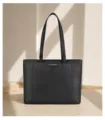 Detail view of the black leather tote bag showing textured cowhide and metallic closure accent. - 35*14*27 / Black