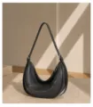 Close-up view of black genuine leather crescent underarm bag showing metal zipper detail. - Black