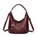 Burgundy leather hobo shoulder bag for women, stylish crossbody tote with braided charm. - Red