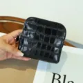 Primer plano detallado que muestra el monedero de cuero con textura de cocodrilo negro. - Negro