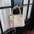 Bolso de mano tejido beige para mujer, elegante bolso con colgante de flor y correa. - Beige