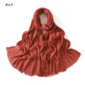 Detailed view of solid color crinkled scarf with tassel fringe, breathable fashion accessory. - Brick Red