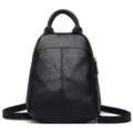 Details of the black genuine leather backpack showing fine texture, durable top handle and zipper. - Black