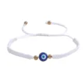 Gros plan sur le bracelet tressé blanc avec un œil turc porte-bonheur et perles dorées. - Mauvais Œil Or (Corde Blanche)