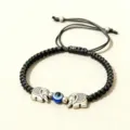 Gros plan sur les details du bracelet tisse noir avec pendentifs elephant et oeil bleu. - Éléphant Argent Œil Résine (Corde Noire)