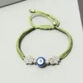 Détail de bracelet cordon tressé vert avec œil maléfique bleu central et breloques main de hamsa. - Main de Fatma Argent (Corde Verte)