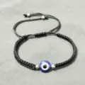Primo piano dettagliato di un braccialetto intrecciato nero con occhio turco e perline. - Malocchio con Perline Finali (Corda Nera)