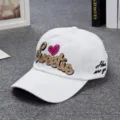 Cappellino da baseball bianco con ricamo Sweetie glitterato e un bel cuore rosa alla moda. - Bianco
