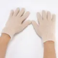 Primo piano di guanti lavorati a maglia beige con morbida consistenza soffice invernale. - Bianco avorio