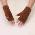 Detailed view of brown cable-knit fingerless gloves, showing delicate texture and warm wear. - One Size / Coffee