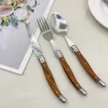 Detailaufnahme des Bestecksets aus Edelstahl mit Holzmaserung, Steakmesser, Gabel, Löffel. - Dreiteiliges Set
