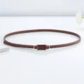 Gros plan sur la fine ceinture en cuir marron avec une boucle en métal doré élégante. - 105cm / Marron
