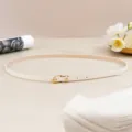 Close-up detail of the slim beige PU leather belt featuring a sleek gold-tone pin buckle. - 105cm / Beige