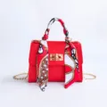 Bolso de mano rojo para mujer con asa de panuelo estampado, cierre dorado y cadena variante. - Rojo