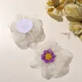 Detail shot of white organza beaded flower accessory with purple yellow center and felt backing. - Beige