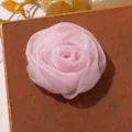 Vue de détail rapprochée d'un accessoire DIY fleur de rose en organza rose, texture douce. - Rose