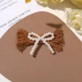 Detalle de horquilla con lazo de perla falsa, accesorio artesanal elegante y chic. - Café