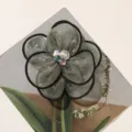Close-up detail of organza fabric flower accessory with black piped edge and sparkling rhinestones. - Grey Green