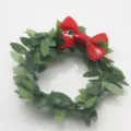 Plan détaillé d'un rond de serviette de Noël avec feuilles artificielles vertes et nœud rouge. - Boucle de Serviette Couronne Nœud de Noël
