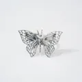Gros plan detaille du papillon creux en metal argente, texture accessoire exquis vue. - Argent
