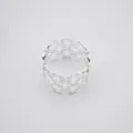 Gros plan sur le rond de serviette argenté à motif de diamant évidé et texture métallique. - Argent