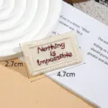 Detailed shot of beige embroidered patch tag with red text for DIY garment accessories. - Nothing / Apricot