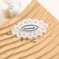 Primo piano di toppa in tessuto di pz fiore di pizzo bianco con etichetta handmade su vassoio. - Stile 6 (Fiore a Cinque Petali)